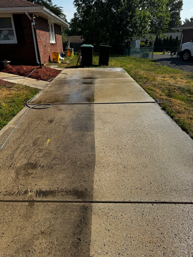A concrete walkway with one clean stripe cut through the dirt by a surface cleaner