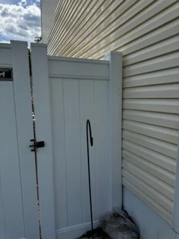 A clean white vinyl fence gate beside the house