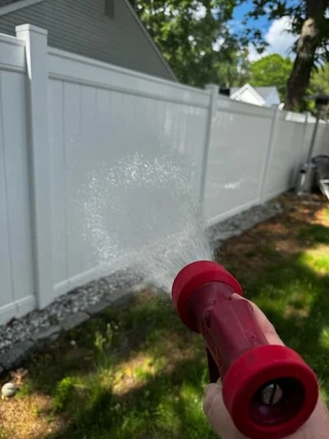 Rinsing a white vinyl privacy fence
