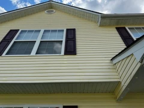 A clean yellow gable wall with dark shutters